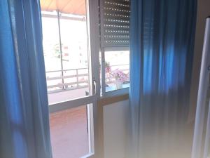 una ventana abierta con cortinas azules en una habitación en Pilgrim Rooms, en Redondela