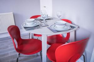 una mesa blanca con sillas rojas y copas de vino en Beach House in Berwick Upon Tweed - 2 Double Bedrooms, en Spittal