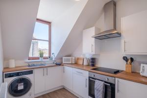 cocina con armarios blancos, lavadora y secadora en Summerfield Stay - SJA Stays - Modern 1 Bed Apartment en Aberdeen