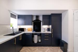 a kitchen with black cabinets and white counter tops at Willowstay - SJA Stays - Modern 2 Bed Apartment in Aberdeen