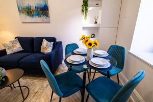 ein Wohnzimmer mit einem blauen Sofa, einem Tisch und Stühlen in der Unterkunft Willowstay - SJA Stays - Modern 2 Bed Apartment in Aberdeen