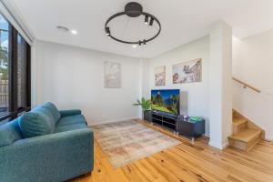 sala de estar con sofá azul y TV en Coastal Elegance, Torquay, en Torquay