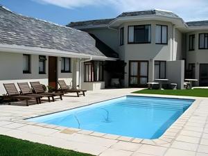 a swimming pool in front of a house at Sandbaai Country House in Hermanus