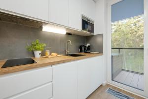 a kitchen with white cabinets and a sink and a window at Lighthouse Hotel Apartment Next to the Marina by Renters in Mrzeżyno