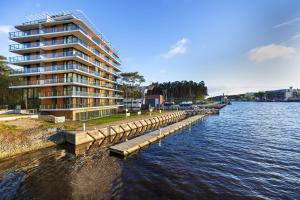 a building next to a body of water with a dock at Lighthouse Hotel Apartment Next to the Marina by Renters in Mrzeżyno