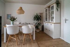 een keuken met een tafel en witte stoelen bij Ferienwohnung Heijenga, 45223 in Jemgum