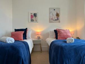 - une chambre avec 2 lits dotés d'oreillers bleus et rouges dans l'établissement Stunning 2-Bed Apartment in Shoreham-by-Sea, à Shoreham-by-Sea