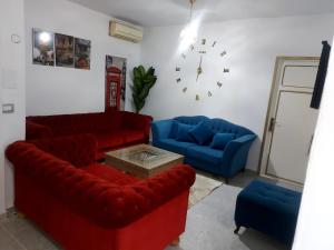 sala de estar con sofás rojos y azules y reloj en Blue hostellerie, en Le Bardo