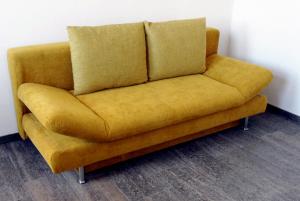 a yellow couch sitting in the corner of a room at Im Bahnhof - Gästezimmer - in Weikersheim