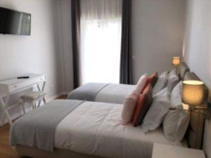 a bedroom with a bed with a desk and a window at Silver Seahorse Garden Retreat in Peniche