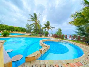 een zwembad met blauw water en palmbomen bij Mfalme Beachfront Apartments in Mombasa