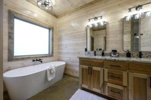 a bathroom with a tub and a sink and a mirror at Morning Roast Cabin in Broken Bow