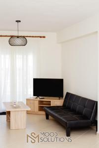 a living room with a black couch and a tv at Polys Polychrono MoodSolutions Living in Polykhrono