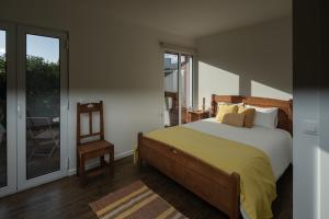 a bedroom with a bed and a chair and a window at Quinta do Ferreiro in Ponta Delgada