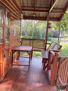 une terrasse couverte avec deux bancs, une table et des bancs dans l'établissement เชียงคานเรือนไม้ รีสอร์ท, à Amphoe Chiang Khan