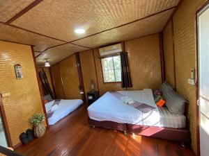 a bedroom with two beds in a room at เชียงคานเรือนไม้ รีสอร์ท in Amphoe Chiang Khan