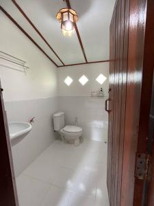 a white bathroom with a toilet and a sink at เชียงคานเรือนไม้ รีสอร์ท in Amphoe Chiang Khan