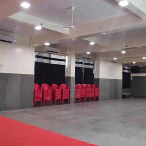 a row of red chairs in a room with curtains at Kamala Shanti Palace, Jule in Solapur