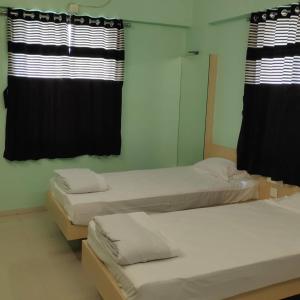 two beds in a room with black curtains at Kamala Shanti Palace, Jule in Solapur