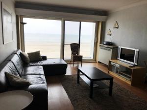 a living room with a couch and a large window at Appartement voor gezin in Middelkerke