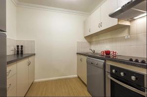 a kitchen with white cabinets and a stove top oven at Narnia in Northbridge - One Bedroom in Perth