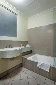 a bathroom with a bath tub and a sink at Narnia in Northbridge - One Bedroom in Perth