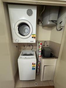 a small kitchen with a washing machine and a sink at Narnia in Northbridge - One Bedroom in Perth