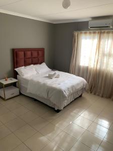a bedroom with a large white bed and a window at Proventures Self-catering House in Ondangwa