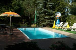 a swimming pool with an umbrella and a table and chairs at Dom z basenem nad Narwia in Szablak