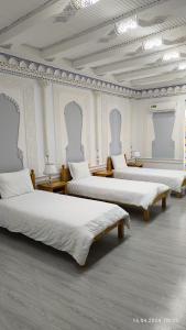 three beds in a room with white walls at Bibikhanum Hotel in Samarkand