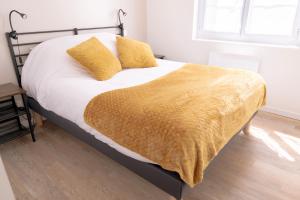 un letto con una coperta gialla sopra di La Vie En Gîte (Le Vintage) a Sainte-Florence