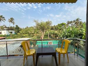 a balcony with a table and two yellow chairs at Anand Heritage Villa in Nagaon