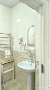 une salle de bain blanche avec un lavabo et un miroir dans l'établissement Bibikhanum Hotel, à Samarcande