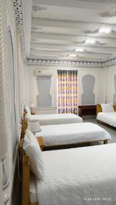 Habitación con 4 camas y sábanas blancas. en Bibikhanum Hotel en Samarcanda