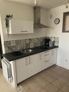 a kitchen with white cabinets and a sink at Studio vue sur mer avec véranda - Roscoff in Roscoff