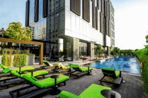 een zwembad met groene ligstoelen en een gebouw bij Revier Hotel - Dubai in Dubai