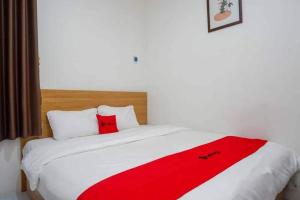 a bed with a red blanket on top of it at Ilfa Guest House syari'ah in Jatiwangi
