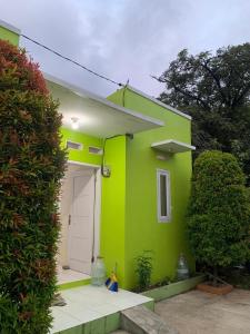 a green house with a white door in a yard at Ilfa Guest House syari'ah in Jatiwangi