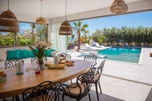 a dining room with a table and chairs and a swimming pool at New Luxury Beach Villa in Duće