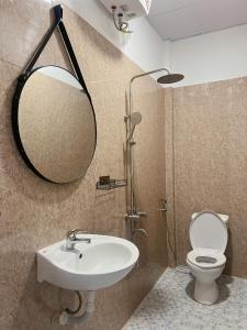 La salle de bains est pourvue d'un lavabo, d'un miroir et de toilettes. dans l'établissement Neko Homestay Hue, à Hue