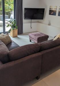 a living room with a brown couch and a flat screen tv at Sonnendeck exklusives Haus in Meerbusch - Wellness Oase Whirlpool & Grill in Meerbusch