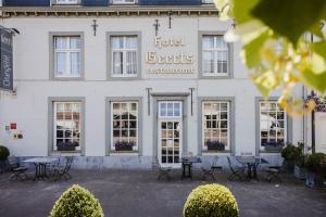 a white building with tables and chairs in front of it at Hotel Geerts in Westerlo