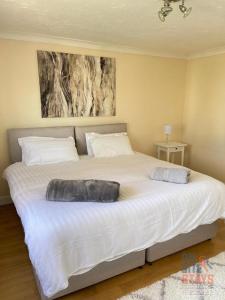 a large white bed in a bedroom with a painting on the wall at On Site Stays - Cosy ground floor 2 bed with Wifi and lots of Parking in Colchester