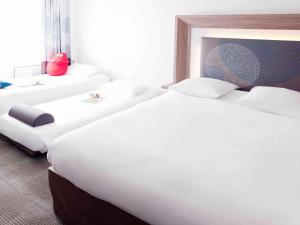 a row of beds in a hotel room at Novotel Bordeaux Lac in Bordeaux