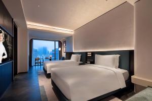 two beds in a hotel room with a view at Sofitel Shanghai North Bund in Shanghai