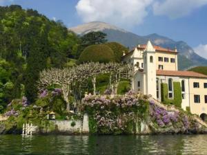 a house on an island in the water with flowers at Lago di Como - home holiday in Zelbio
