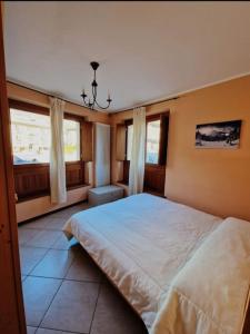 een slaapkamer met een groot bed en 2 ramen bij Appartamento a Bardonecchia in Bardonecchia