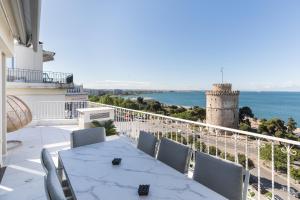 a balcony with a table and a view of the ocean at Aria, Lux seafront apt with White Tower view in Thessaloniki