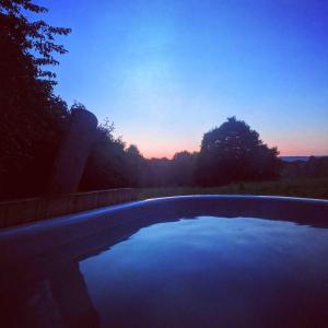 an empty swimming pool with a sunset in the background at Oku Wooden Pod, Newburgh Priory Estate in York