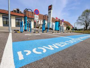 a parking lot with a blue painted sign on the street at ibis Haguenau Strasbourg Nord in Haguenau